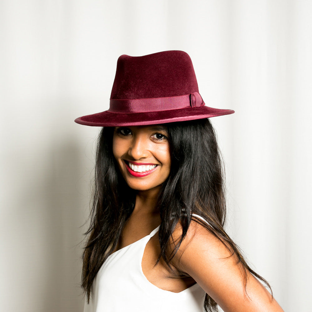 Woman wearing a burgundy hat against a plain background