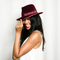 Woman wearing a burgundy fedora hat against a white background