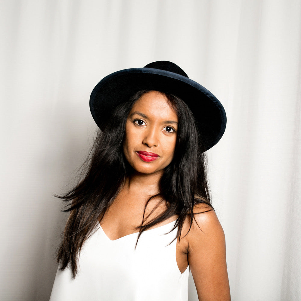 Woman wearing a blue hat with a red lips pin against a white background