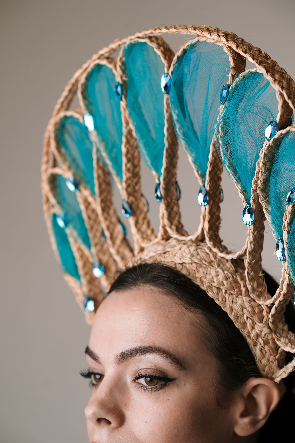Woman wearing a decorative headpiece with blue feathers and gold accents.