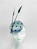 Black and ice blue polka dot pillbox hat on a mannequin head against a light gray background