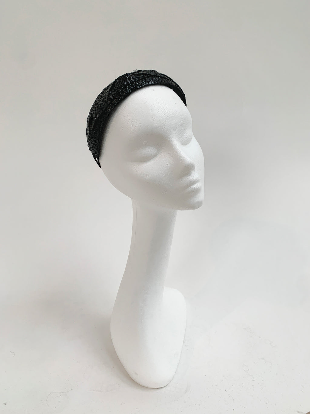 Black patent headband on a white mannequin head against a light gray background