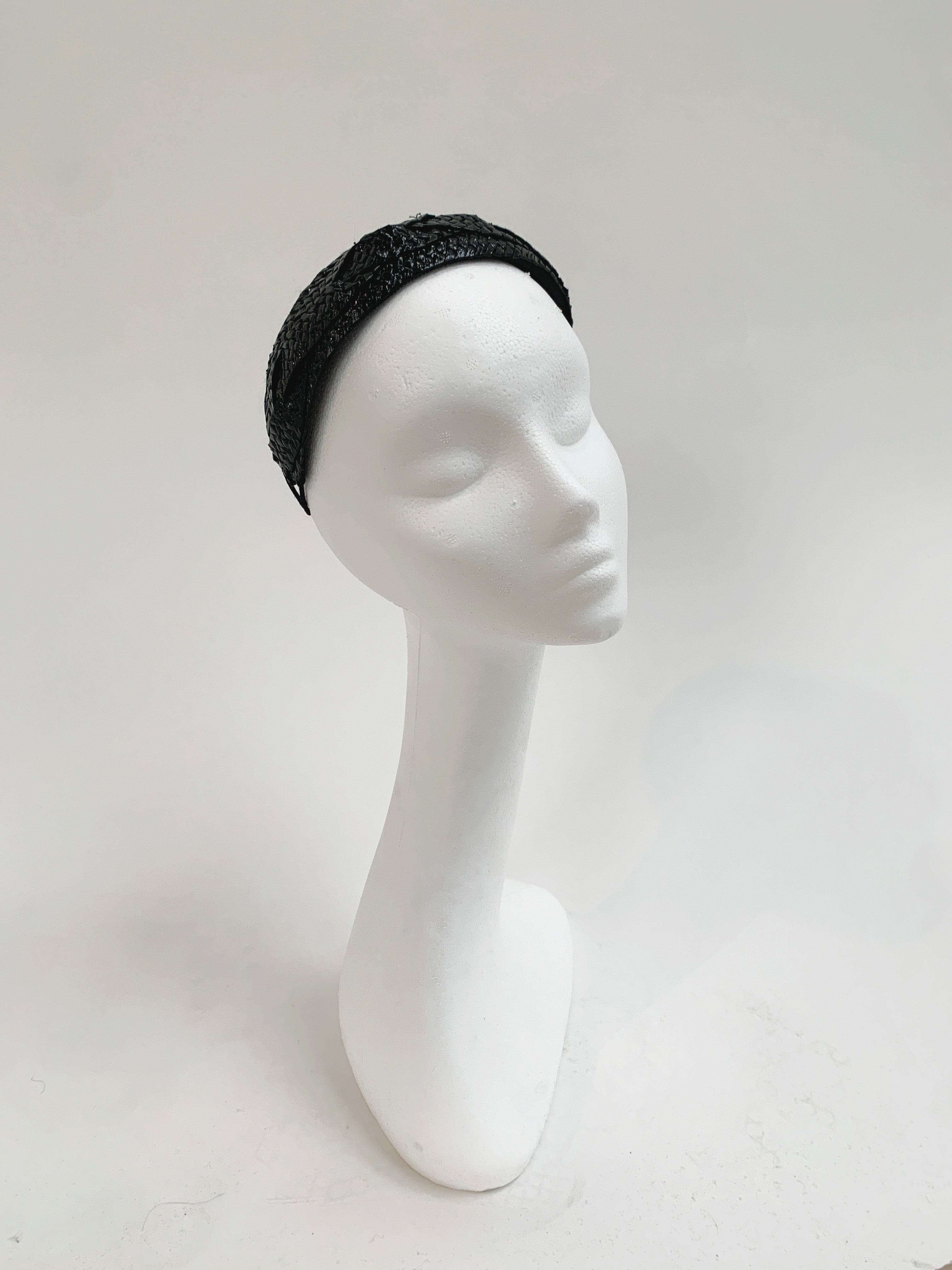Black patent headband on a white mannequin head against a light gray background