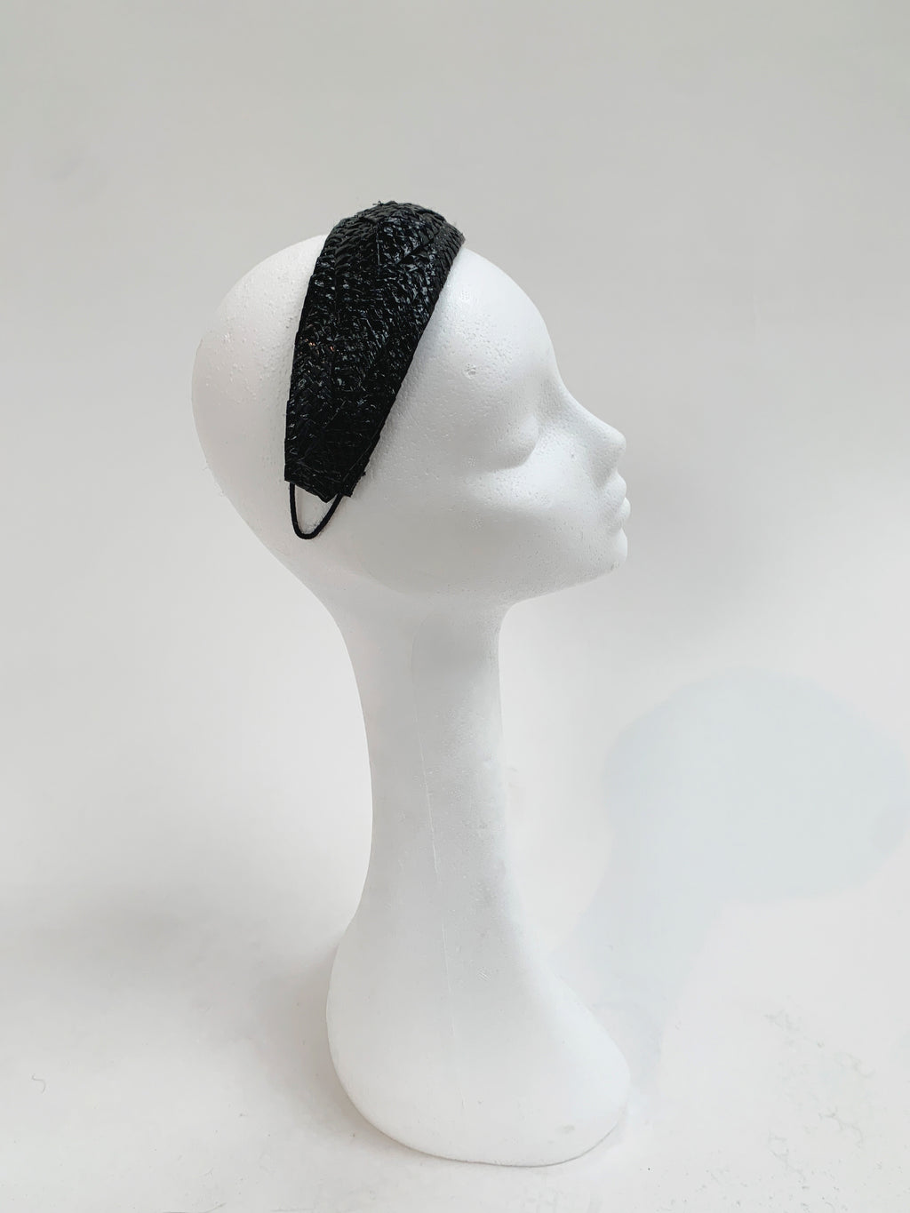 Black patent headband on a white mannequin head against a white background