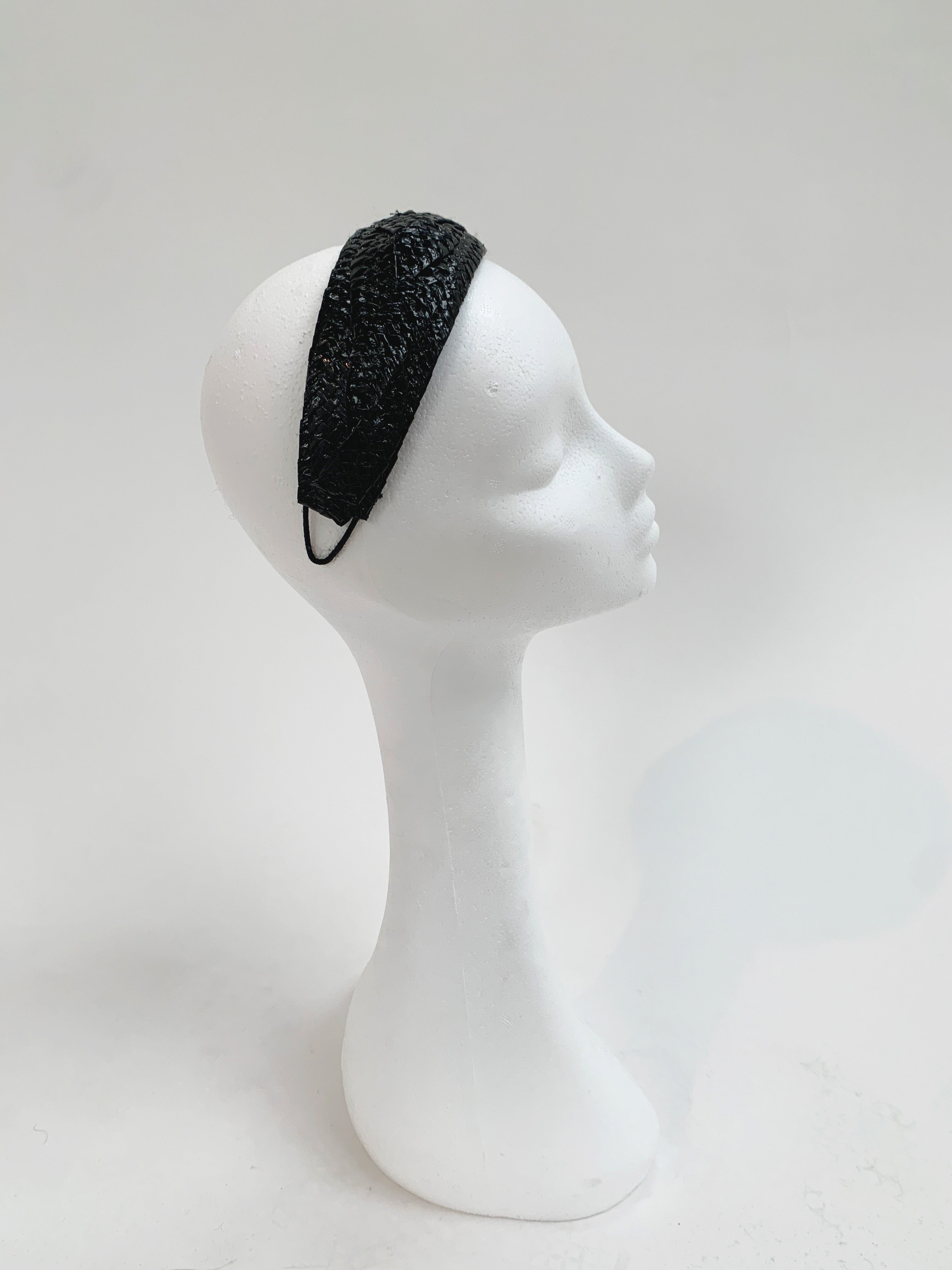 Black patent headband on a white mannequin head against a white background