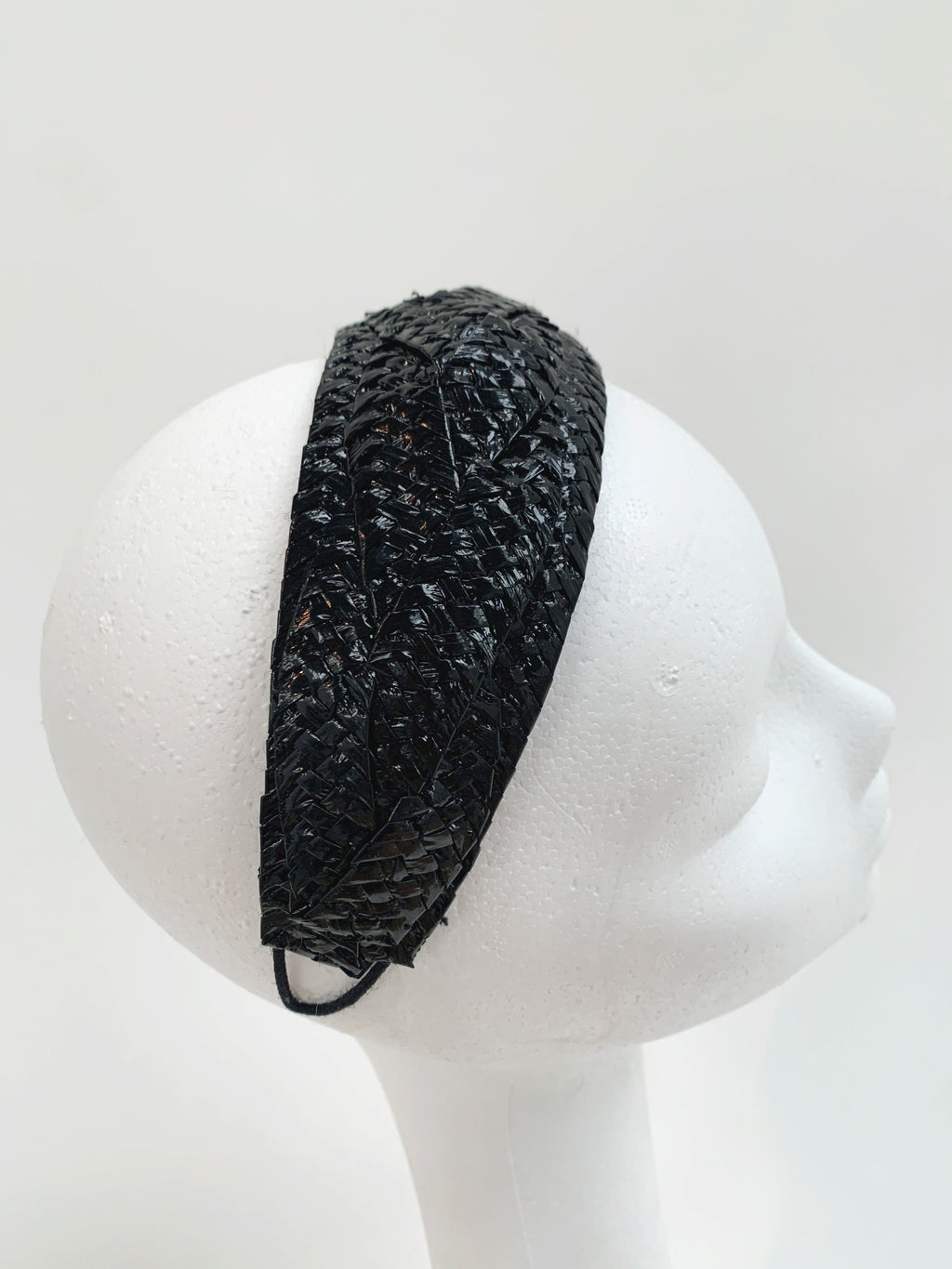 Black woven headband on a mannequin head against a white background