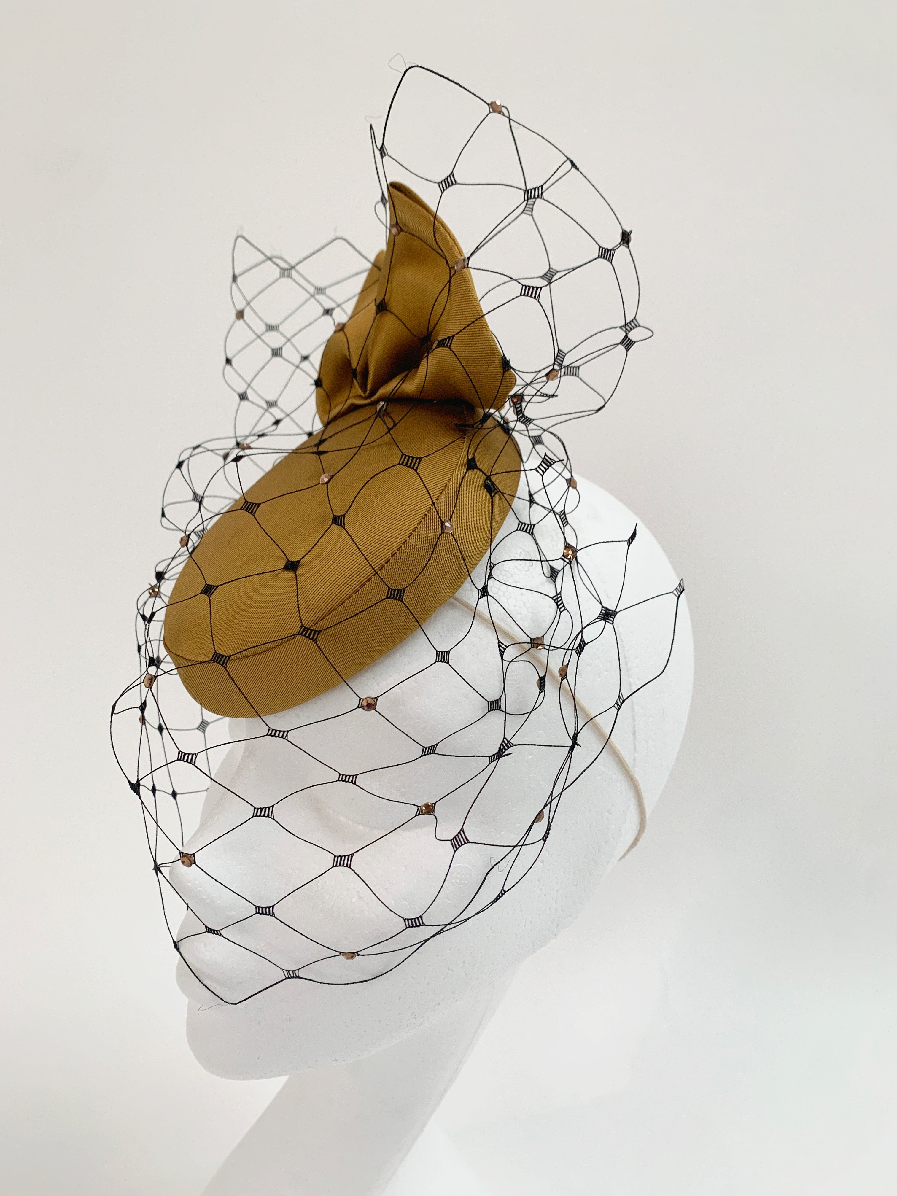 Golden headpiece with a black wire mesh on a white background