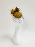 Golden bow cocktail hat on a mannequin head with a white background