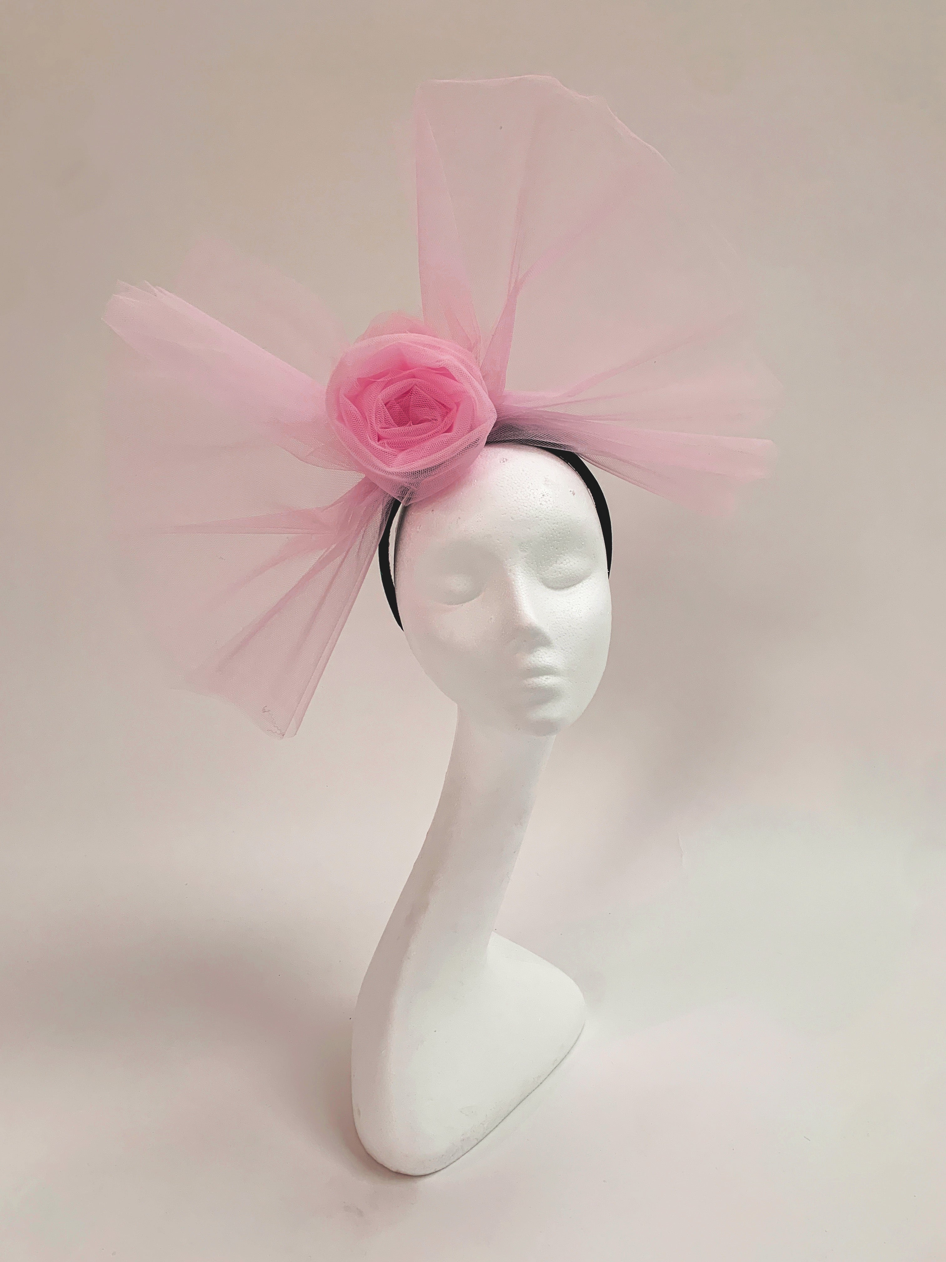 Mannequin head with a pink floral headband on a light pink background