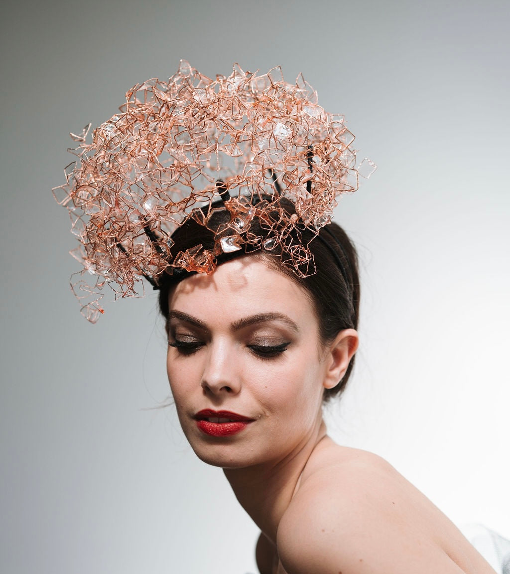 Woman wearing an intricate headpiece against a neutral background