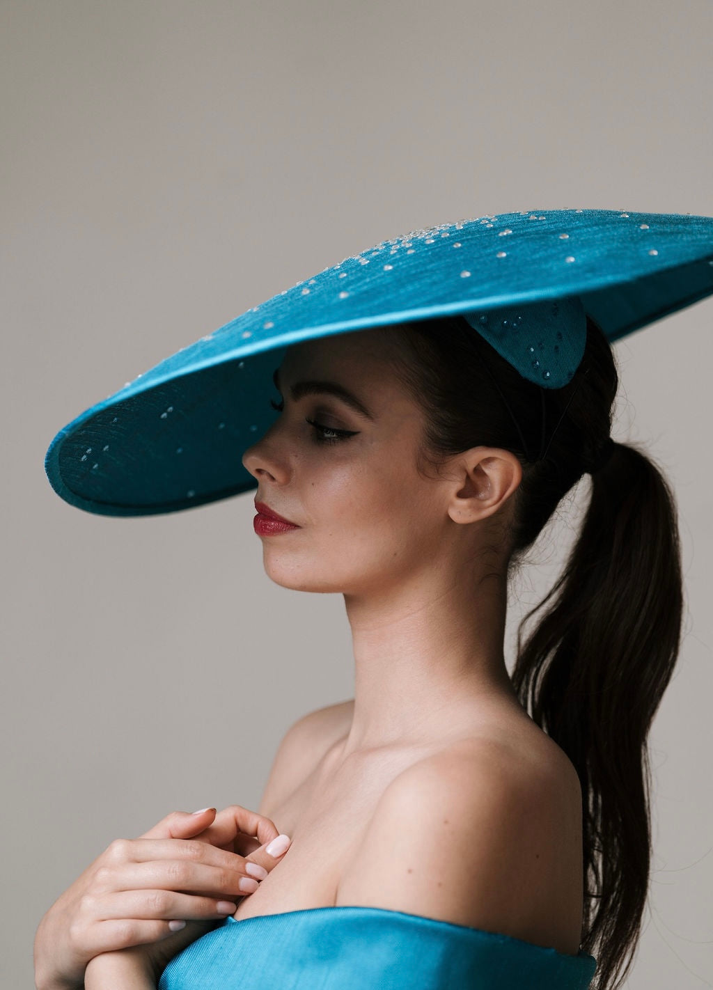 Woman wearing a blue hat with a textured surface against a neutral background